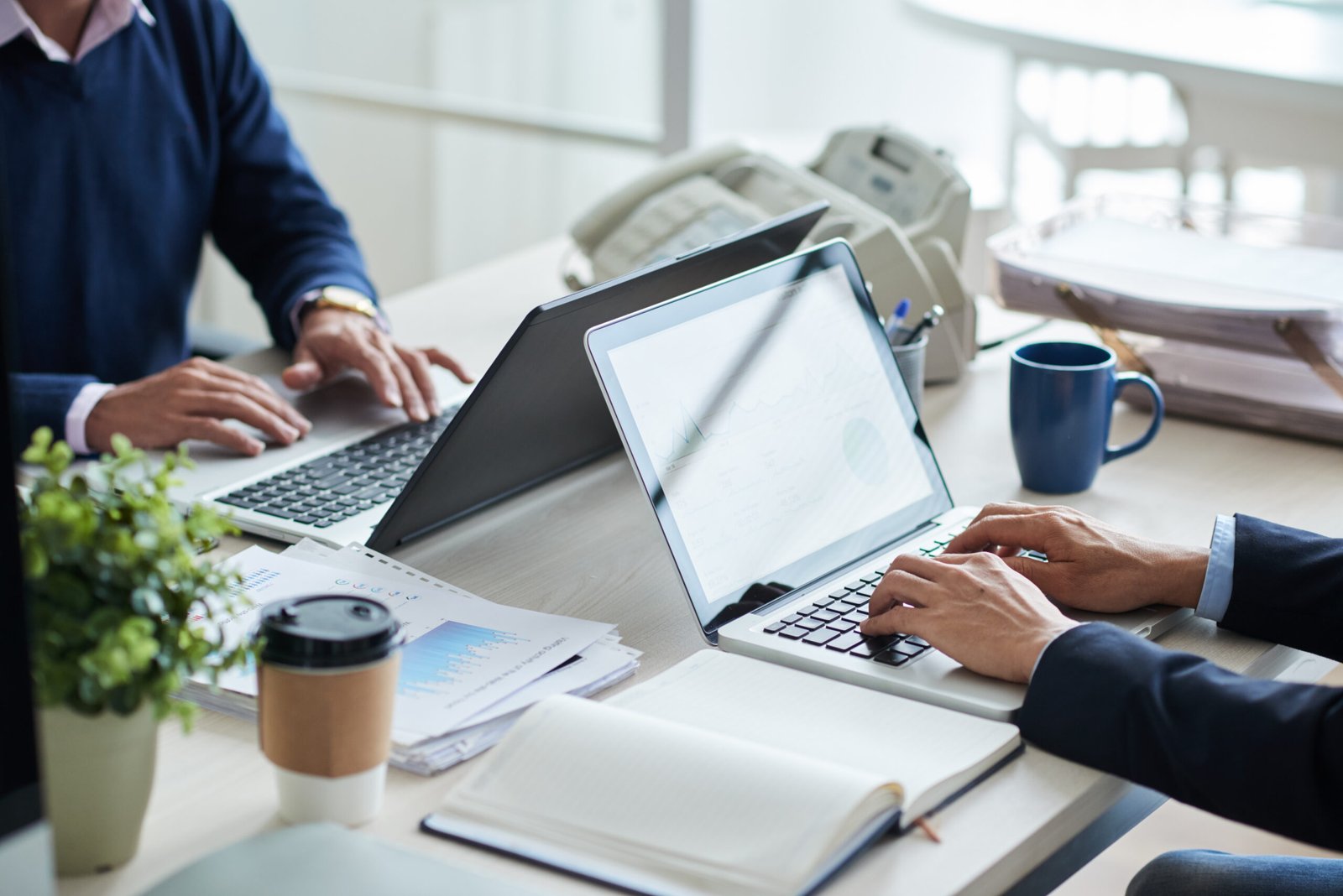 Cropped image of business people working on laptops in office